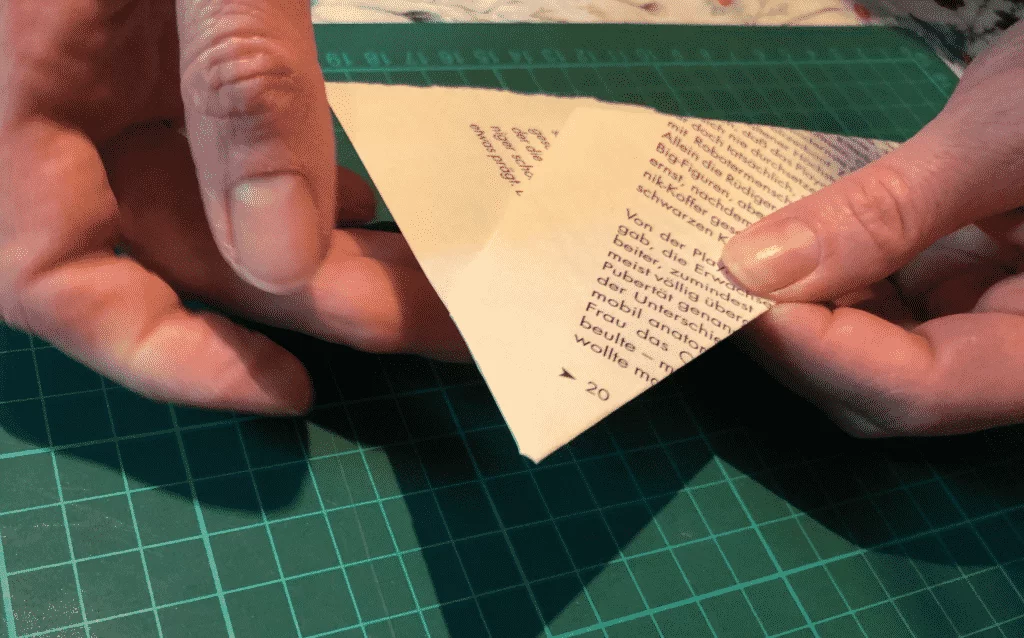 3. Falte: unten soll jetzt noch eine kleine Ecke überstehen, diese scharf über die Seite in das Buch reinfalten, damit halten die ersten beiden Falten